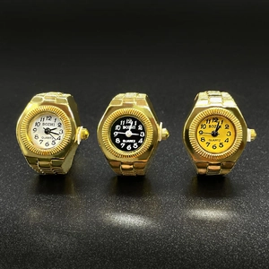 Three gold quartz ring watches with white black and gold dials on dark background