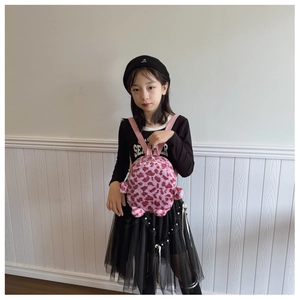 Close-up of a pink leopard print plush backpack worn by a child in a home setting