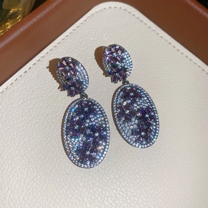 Detail of oval drop earrings with purple zircon flower and full pavé stones on silver needles