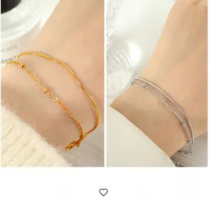 Detail of minimalist double-layered bracelet with snake chain and gold beaded accents