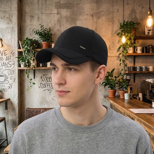 Klassische schwarze Herren-Baseballkappe mit Metallakzent in einem gemütlichen Café