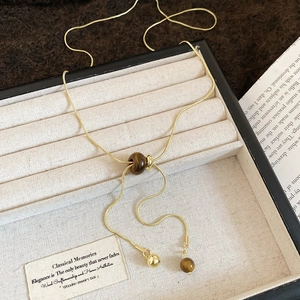 Detail of adjustable gold necklace with tiger eye beads on soft velvet display tray