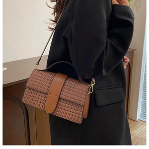 Close-up of brown woven PU leather shoulder bag with fine texture and gold hardware