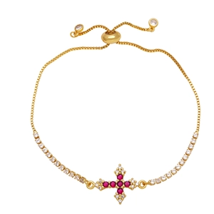 Detail view of gold cross bracelet with ruby-red stones and sparkling zircons