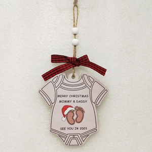 Close-up of baby onesie wooden ornament with Merry Christmas 2025 print and bow