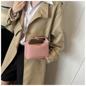 Detail of pink woven crossbody bag featuring gold hardware and a slender shoulder strap