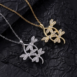 Close-up of triple dragonfly pendant with cubic zirconia stones on textured background