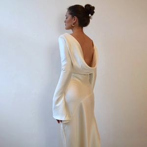 Detail of elegant white satin backless evening gown with a high slit and sleek long sleeves