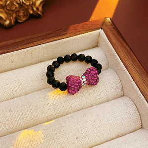 Detail of black beaded ring with a sparkling purple rhinestone bow on velvet lining