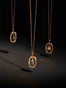 Macro detail of gold letter pendants A S M with colorful zircon stones on fine chains