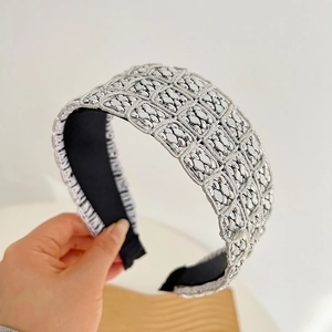 Detail of silver metallic textured knot headband with a wide geometric braided pattern