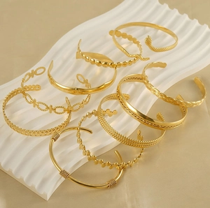 Close-up of assorted 18K gold-plated C-shaped bracelets with snake and woven textures