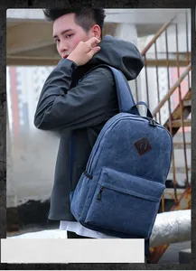 Close-up of blue canvas backpack with brown leather patch on outdoor concrete stairs