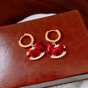 Vista macro degli orecchini a cavallo a dondolo placcati oro 18k con smalto rosso e zirconi