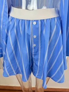 Detail of blue and white striped shorts with elastic waistband and decorative buttons