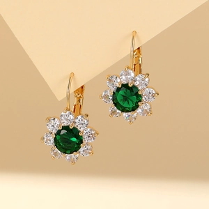 Macro shot of gold floral earrings with a large green zircon stone and white crystals