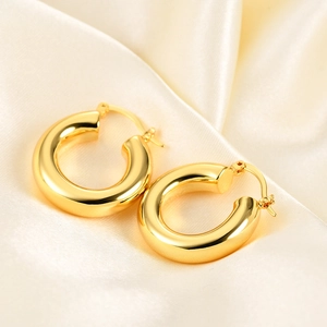 Detailed close-up of chunky gold hoop earrings with polished finish on silk fabric
