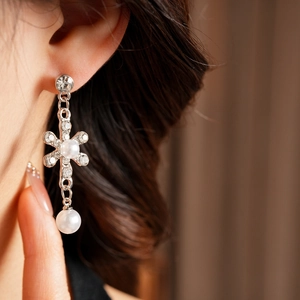 Detailed close-up of a silver flower pearl earring with rhinestones on a model