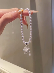 Detail of hand-held pearl necklace with silver flower basket pendant and zircons