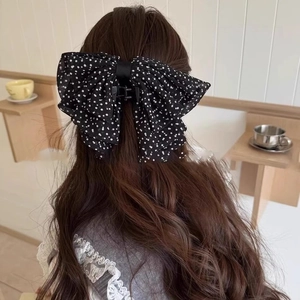 Gros plan d'une pince à cheveux à nœud papillon à pois français sur cheveux longs bouclés