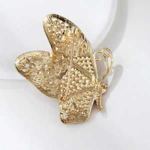Detailed back view of gold butterfly brooch showing filigree design and sturdy safety pin