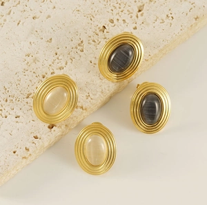 Close-up of vintage 18K gold plated earrings with beige and grey oval natural stones
