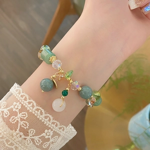 Close-up of beaded bracelet with green jade-like beads and gold fringe charms