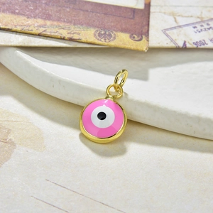 Detail of a pink enamel round Evil Eye pendant with golden rim on a vintage paper