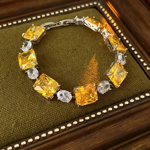 Detailed shot of yellow zircon square pendant bracelet on green velvet frame