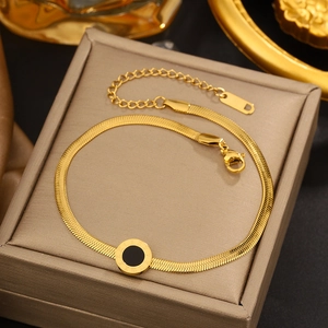 Detail of gold snake chain bracelet featuring a black circular Roman numeral charm