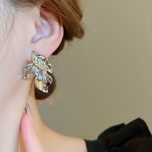 Macro shot of silver textured leaf stud earring worn by model showing metallic details