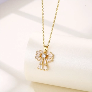 Detail of 18k gold plated necklace featuring a zircon bow pendant on white pedestal