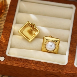 Detail of square gold pearl earrings with butterfly back on velvet jewelry box display