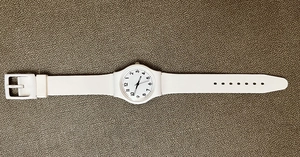 Detail view of a white minimalist quartz watch with a silicone strap and numeric dial