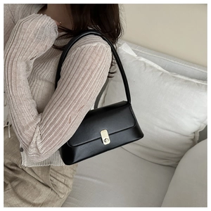 Close-up of minimalist black PU leather baguette bag with elegant gold metal buckle