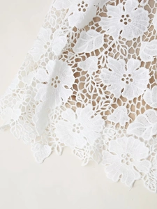 Détail de tissu en dentelle florale blanche avec doublure beige pour robe longue