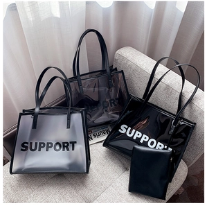 Three transparent PVC tote bags with SUPPORT print displayed on a minimalist gray sofa