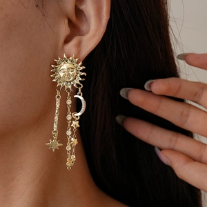 Vintage gold celestial drop earrings with sun moon and star charms worn by a model