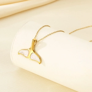 Détail d'un collier avec pendentif queue de poisson dorée sur un support blanc élégant