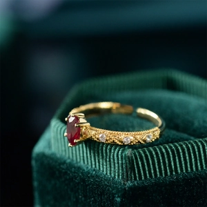 Macro detail of oval red gemstone ring with pavé diamonds on gold adjustable band