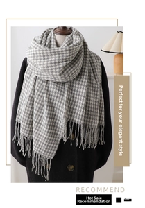 Detail of grey and white houndstooth scarf with classic fringes on a dark wool coat