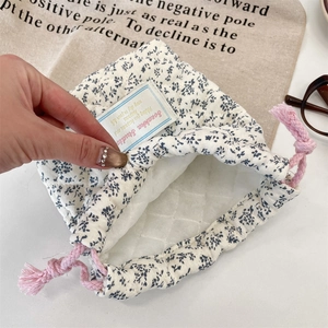 Floral quilted camera pouch featuring blue flowers and a pink drawstring closure detail