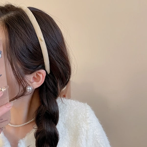Détail du serre-tête beige floqué avec logo Love doré sur texture tricotée