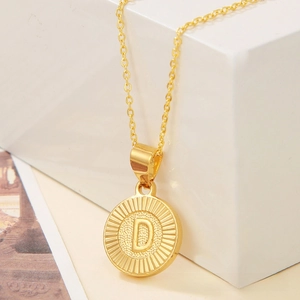 Detailed macro view of a gold-plated coin pendant necklace featuring an embossed letter D