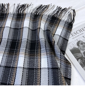 Macro detail of classic black and white plaid scarf with soft long fringe tassels