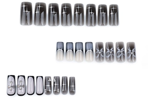 Detail of square press-on nails featuring black ombré, silver crosses, and bow accents