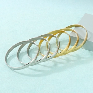 Detail showing gold and silver stacked 8mm stainless steel bracelets on light blue texture