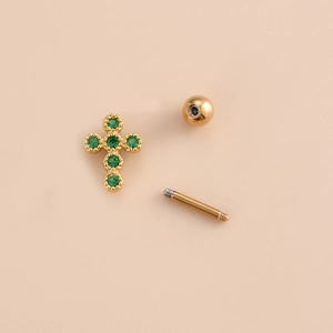 Detailed view of gold cross cartilage piercing stud with green zircon and screw ball back