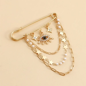 Detail of gold evil eye brooch with tassels, crystals, and layered pearl chains