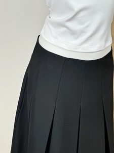 Detailed view of the precise pleats and textile texture on a black pleated skirt